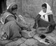 Palestine: Two Palestinian women grinding coffee with a pestle, mortar and sieve, c. 1930